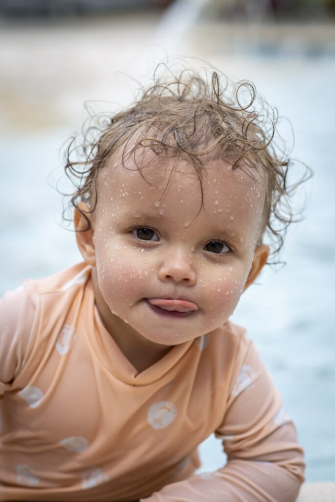 A baby wet from playing in a pool.